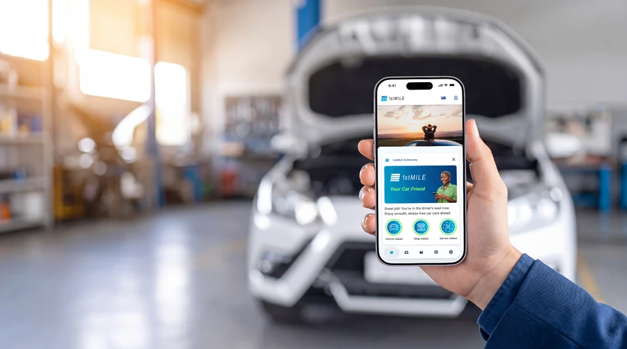 A driver holding a phone that shows the 1stMILE app in a service shop