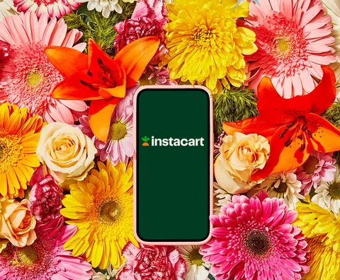 Instacart app on a smartphone surrounded by fresh flowers