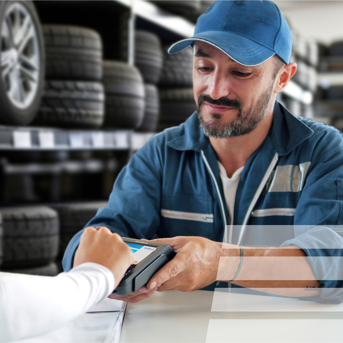 a car shop employee holding a device for a customer to run a credit card