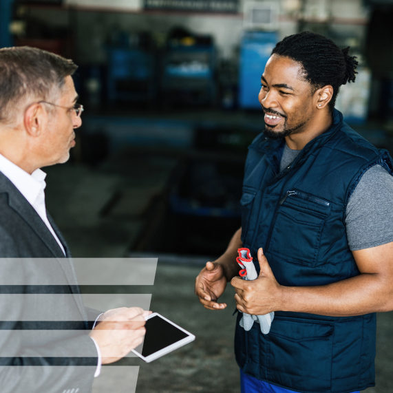 two men talking to each other in an automotive shop